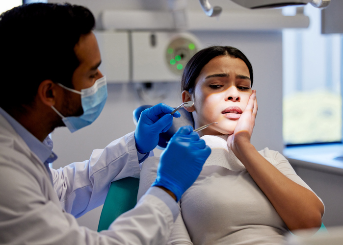 Shot of a young woman experiencing pain and anxiety while having a dental procedure